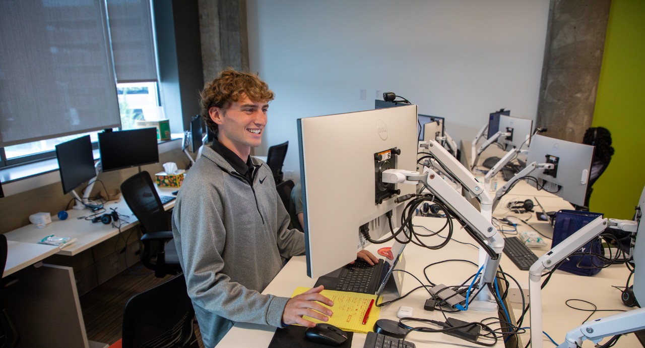 A student works at a computer with schematics on the screen.