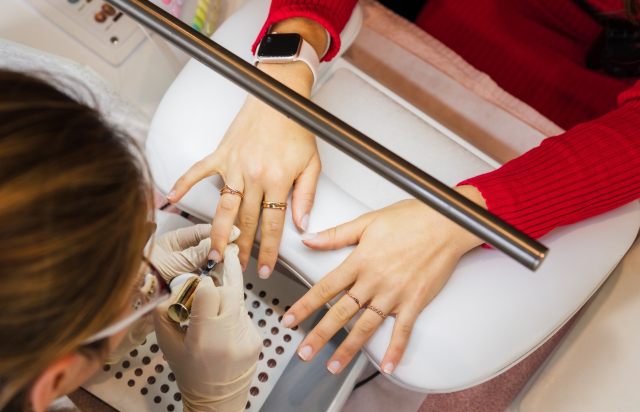 A manicurist applies nail polish to a client's hands
