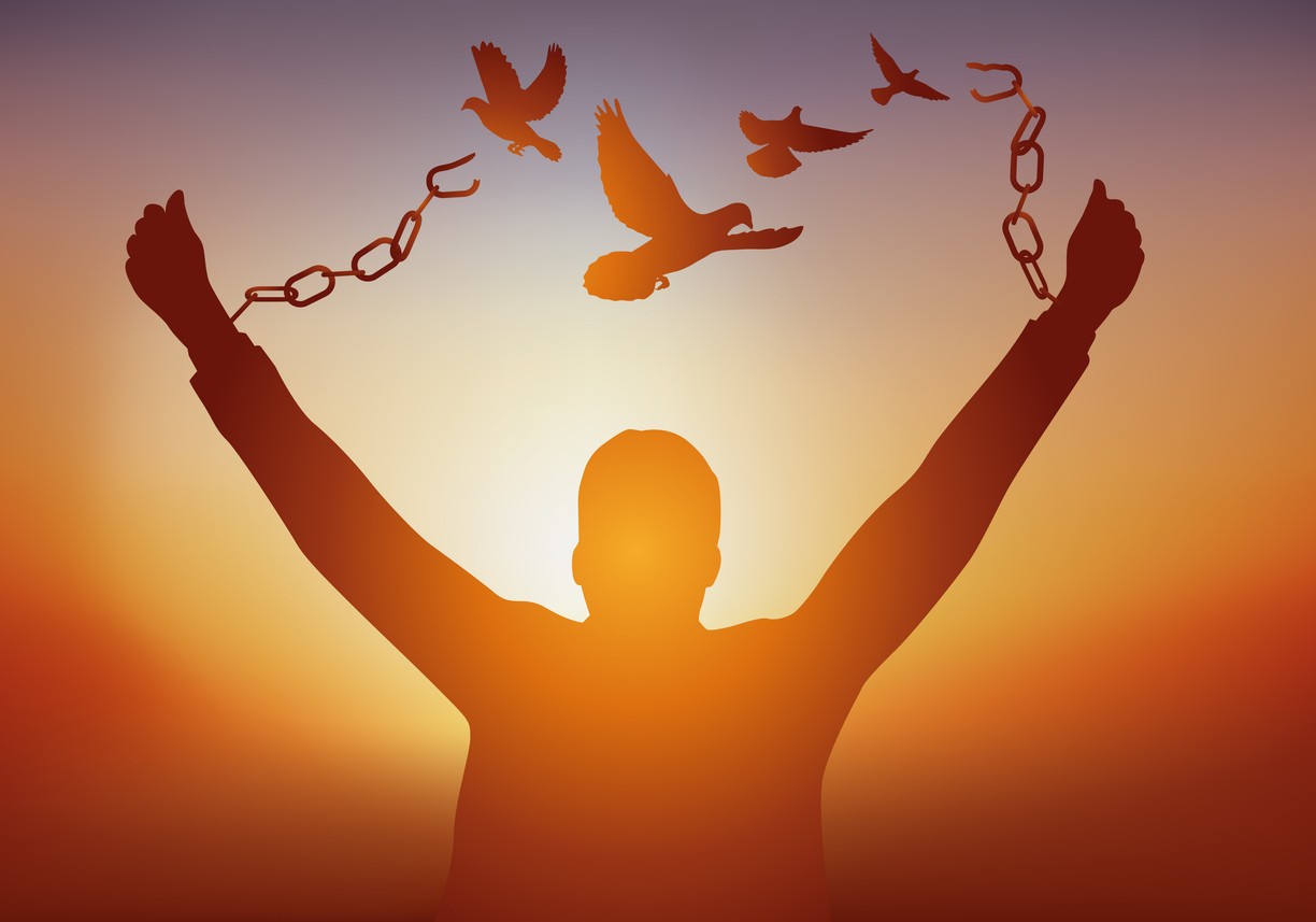 Man standing with arms outstretched, chains broken and doves flying