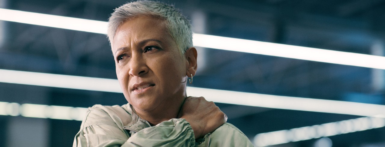 A woman grabs her shoulder in pain