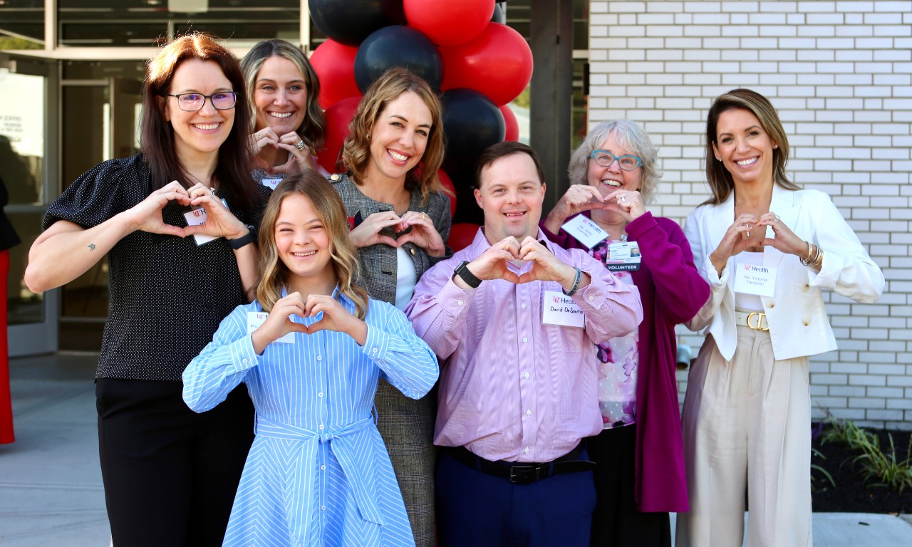 Several people stand with their hands shaped as hearts.