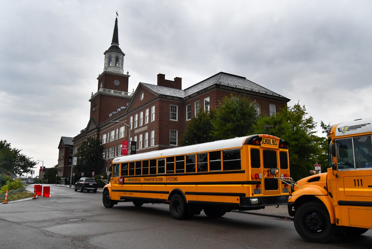 Two yellow school buses pull up in front of Arts and Sciences Hall. 