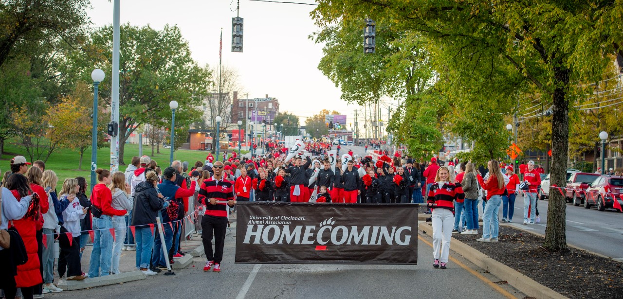 Student Alumni Council members holding the UC Alumni Association Homecoming banner at the front of the 2024 Homecoming parade