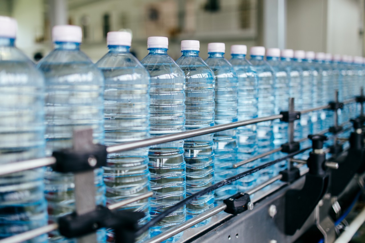 A row of plastic water bottles inside a bottling plant. 