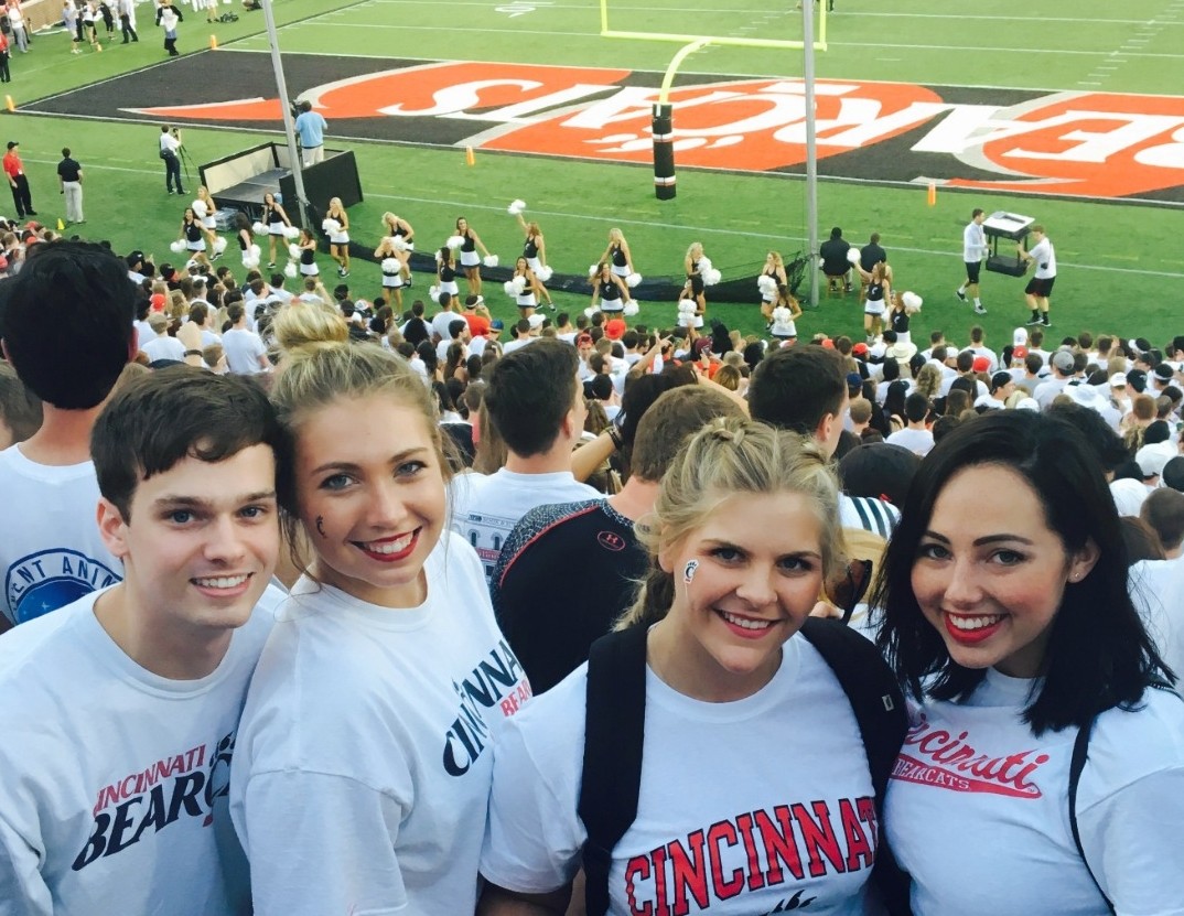 Three UC students pose at a Bearcats football game