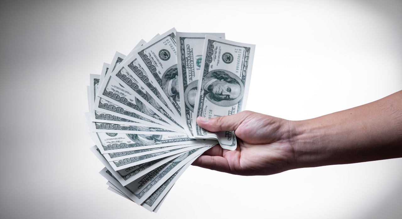 Hand holding cash, how to save money as a college student