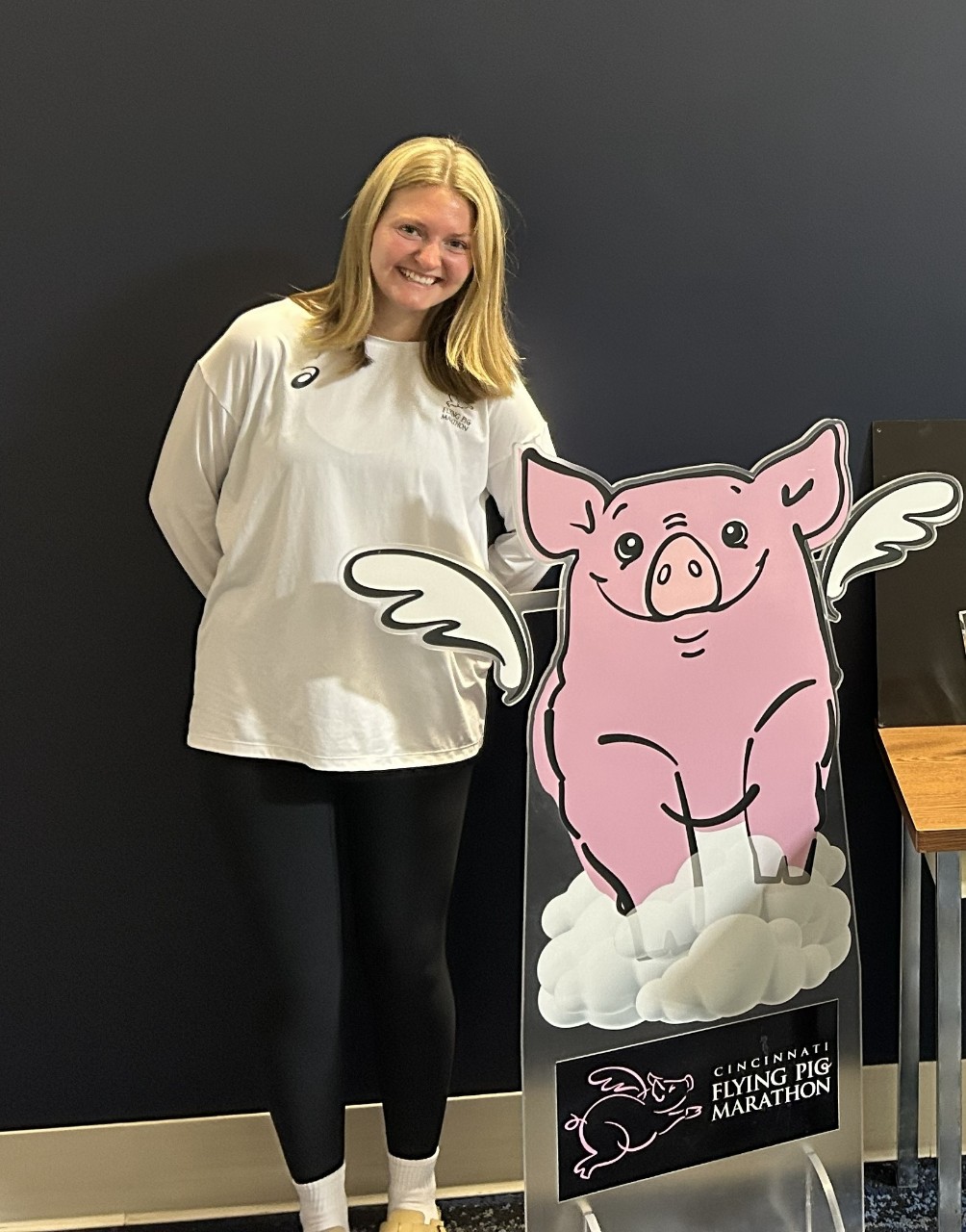 Dylan Eggleton standing next to a cardboard cutout of a pink pig. 