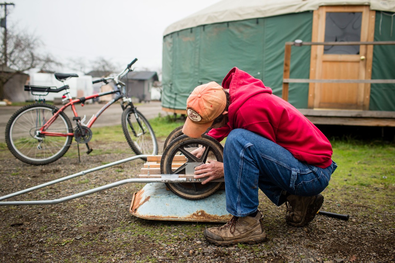 A bicycle with two carts attached to its back sits admidst a group of tiny homes