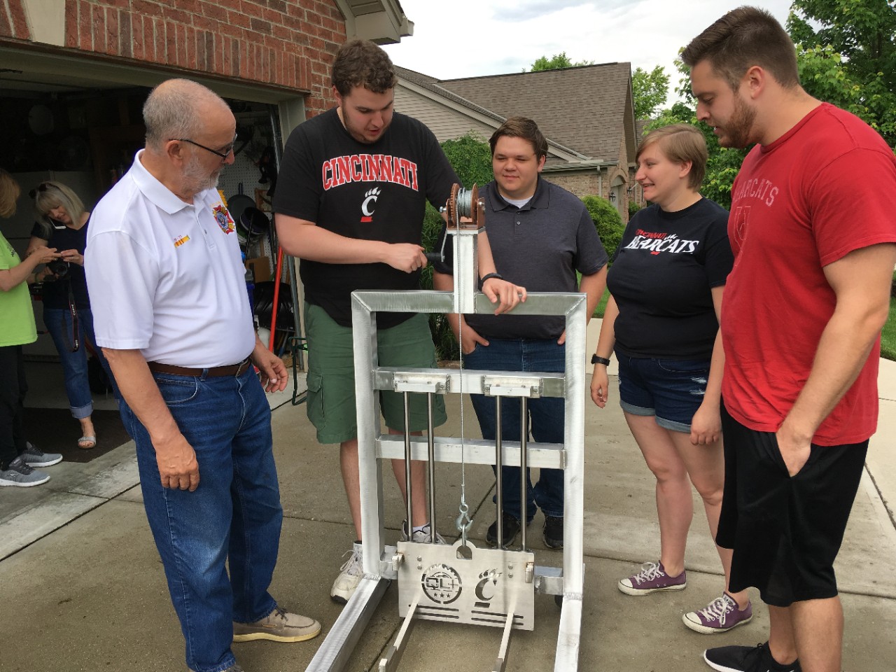 Four UC engineering students deliver a winch to a U.S. Army veteran outside his home.