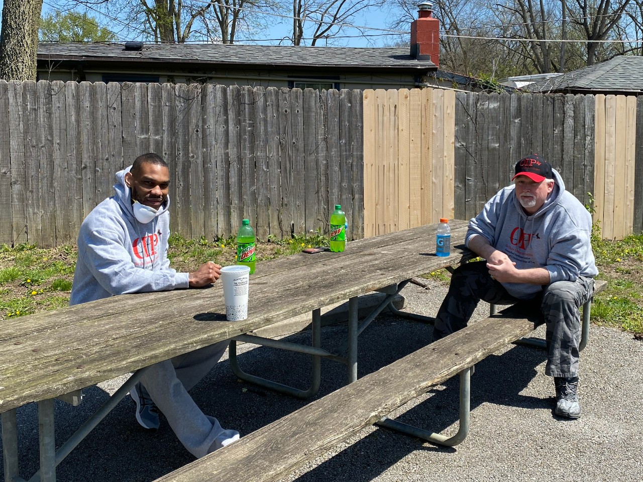 Two men sit at a picnic bench