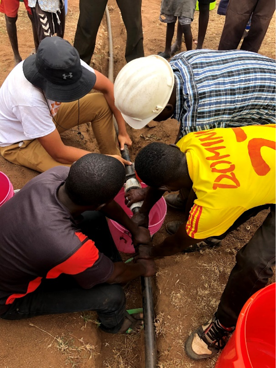 Four people working on a pipe
