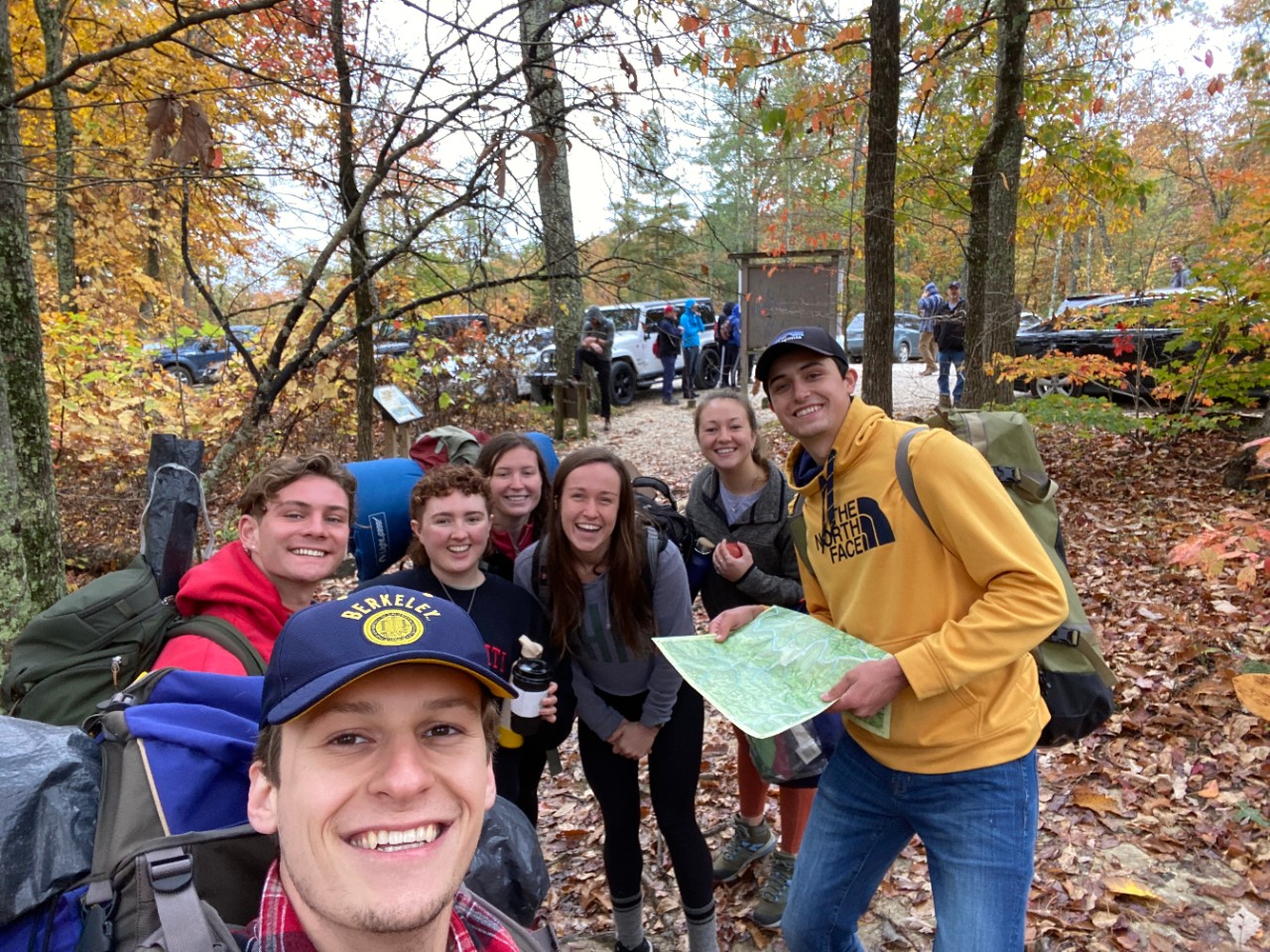 Jake Hemmerle poses with friends outside in a forest.