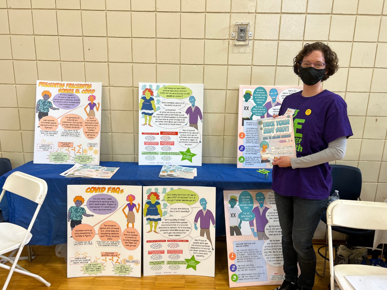 a woman standing by tables of educational materials at a health fair