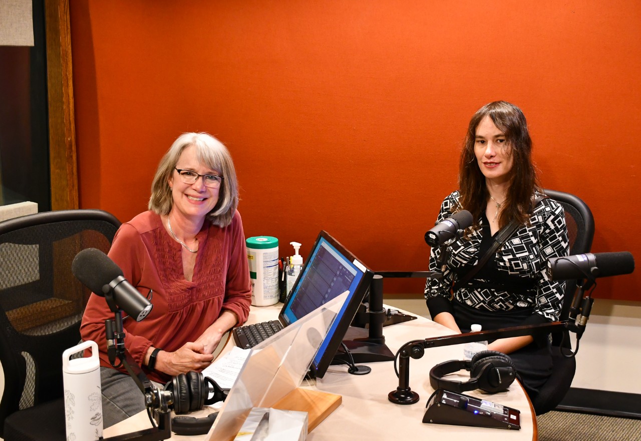 Two people pose for a photo in a radio studio.
