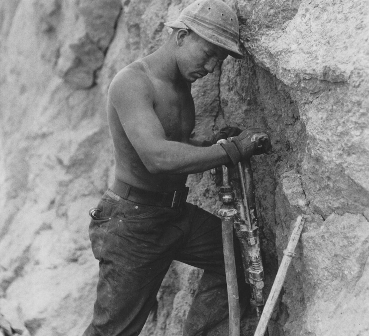 A worker at the Hoover Dam wears two baseball caps dipped in tar as a protective hard hat.