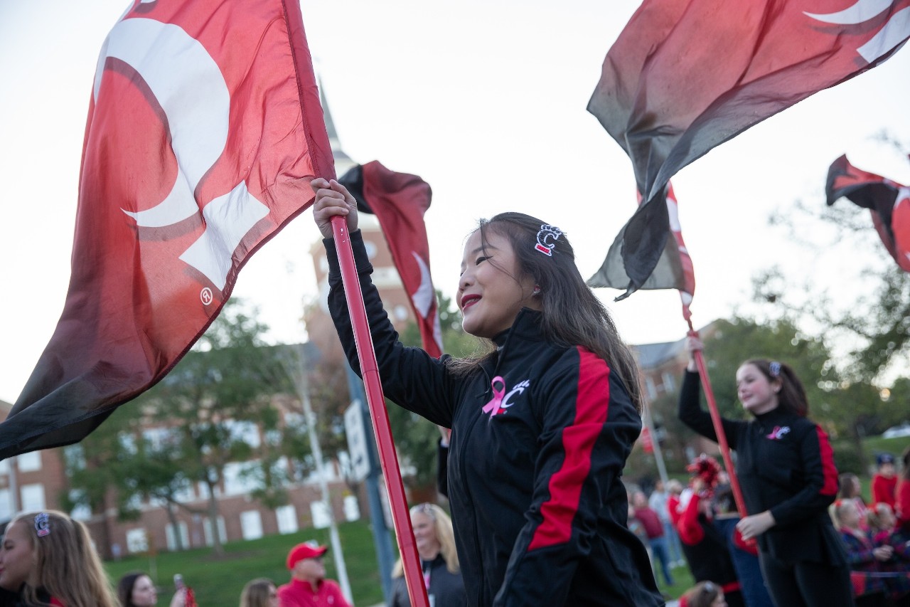 two dance team members shown holding uc flags in homecoming parade
