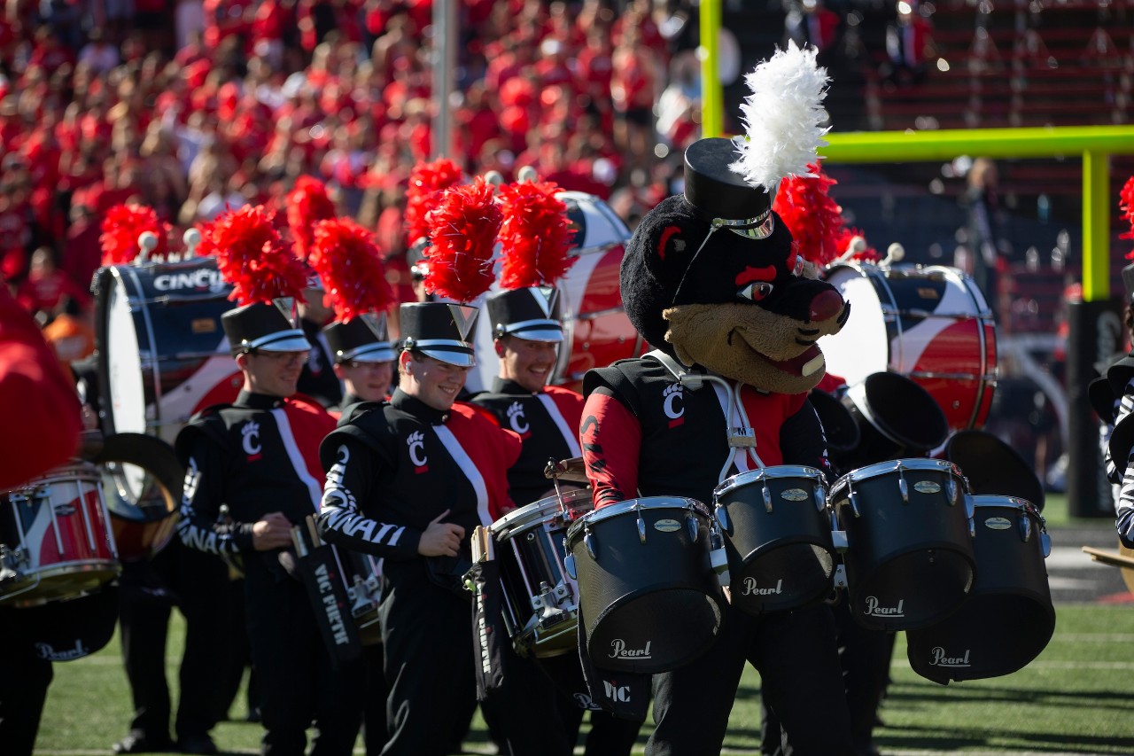 marching band drum corp takes the football field with Bearcat joining in for fun
