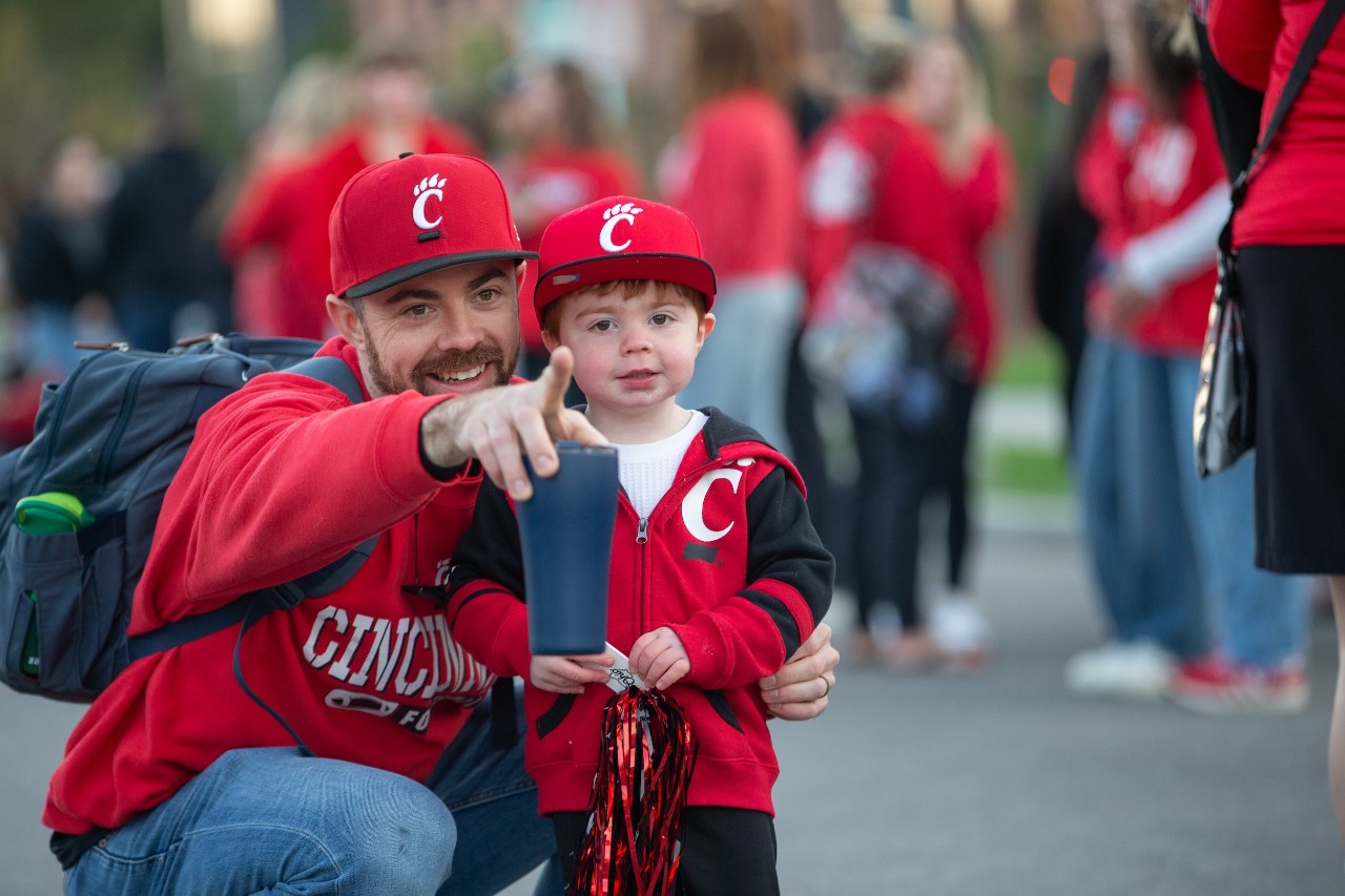 a father with his young son dressed in UC swag at the homecoming parade