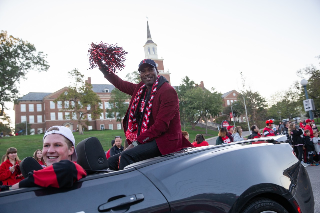 young man ride on car and waves to crowd at homecoming parade