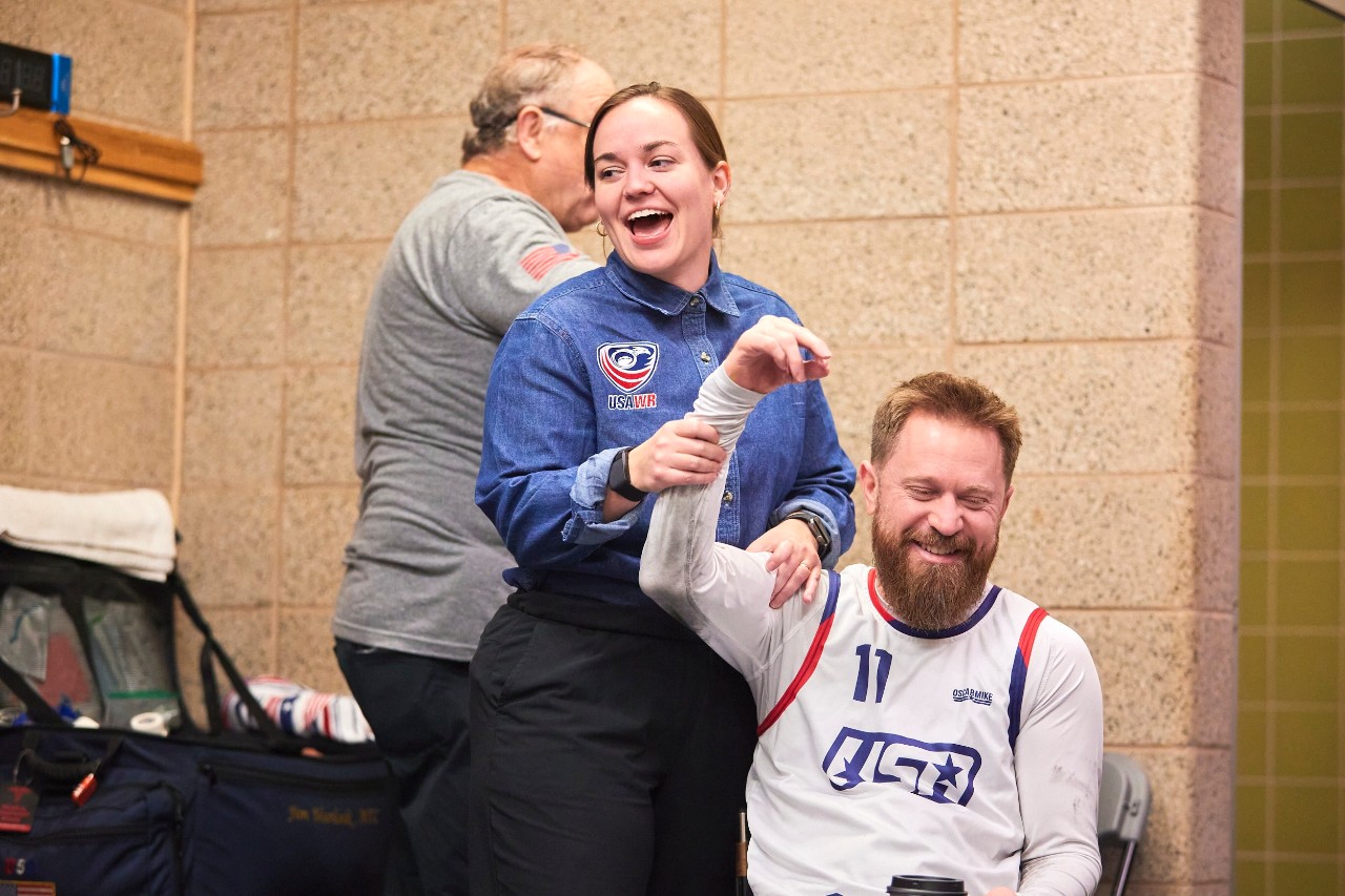 MeMe Earnest-Stanley tends to Team USA's Lee Fredette, examining his arm, during a wheelchair rugby game.