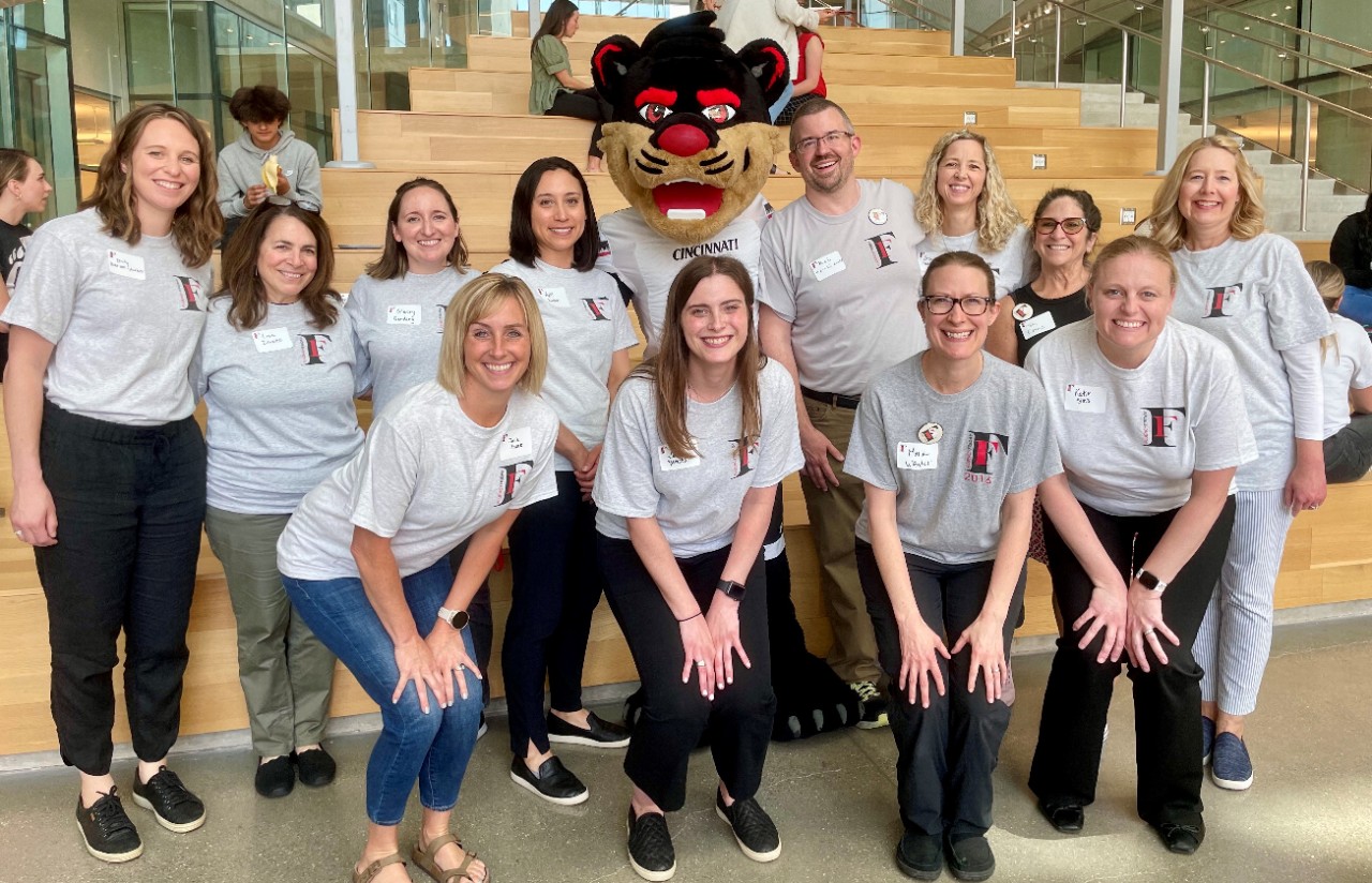 Fluency Friday planning team with the Bearcat mascot in the Health Sciences Building atrium
